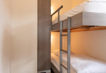 Et lille værelse på glamping med køjeseng, moderne klædeskab og lyse vægge for hyggelig overnatning.