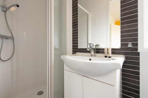 Moderne badkamer met douche, lavabo en spiegel in een gezellige glamping accommodatie.