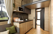 Modern tiny house interior at Urban-Gardens in Belgium, featuring wood paneling, loft, and kitchenette.