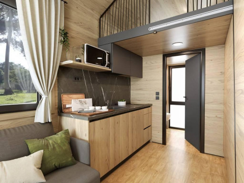 Modernes Tiny-House-Interieur bei Urban-Gardens, Belgien, mit Küchenzeile, Holzdekor und Hochbett.