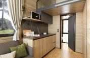 Interno di tiny house moderna all’Urban-Gardens in Belgio, con pannelli di legno, soppalco e angolo cottura.