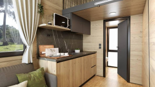 Interno di tiny house moderna all’Urban-Gardens in Belgio, con pannelli di legno, soppalco e angolo cottura.