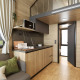 Interno di tiny house moderna all’Urban-Gardens in Belgio, con pannelli di legno, soppalco e angolo cottura.