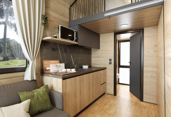 Modern tiny house interieur bij Urban-Gardens in België met hout, kitchenette en een loftgedeelte.