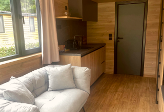 Tiny Home bij Urban-Gardens in België met een comfortabele bank, keukenblok en groot raam.