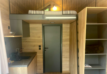 Interieur van Tiny Home bij Urban-Gardens in België, met een slaapvide, keuken en houten muren.