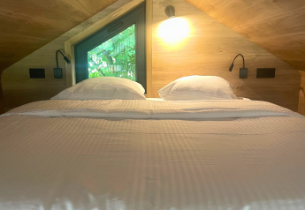 Acogedora zona de dormitorio con cama doble bajo techo inclinado en Tiny Home at Urban-Gardens, Bélgica.