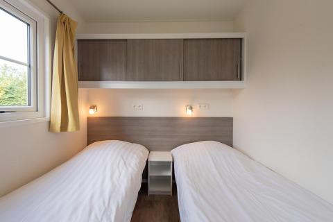 Dos camas individuales con sábanas blancas en Comfort Lodge de Kompas Camping Westende, Bélgica, se permiten perros.