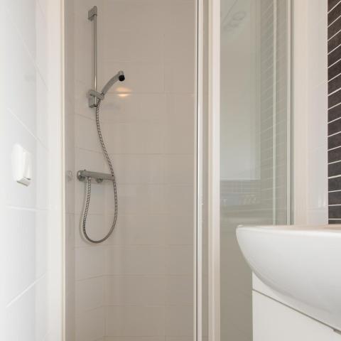Salle de bain moderne avec cabine de douche et douchette à Comfort Lodge, Kompas Camping Westende, Belgique.