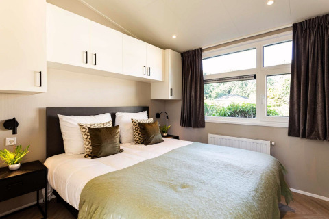 Modern slaapkamer bij Silva Wellness lodge, Bospark Ede, Nederland, met tweepersoonsbed en grote ramen.
