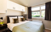 Dormitorio moderno en la cabaña Silva Wellness de Bospark Ede, Holanda, con cama doble y grandes ventanas.