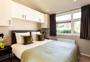 Dormitorio moderno en la cabaña Silva Wellness de Bospark Ede, Holanda, con cama doble y grandes ventanas.
