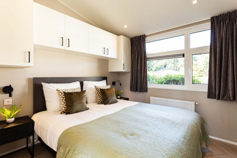 Dormitorio moderno en la cabaña Silva Wellness de Bospark Ede, Holanda, con cama doble y grandes ventanas.