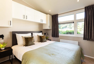 Dormitorio moderno en la cabaña Silva Wellness de Bospark Ede, Holanda, con cama doble y grandes ventanas.