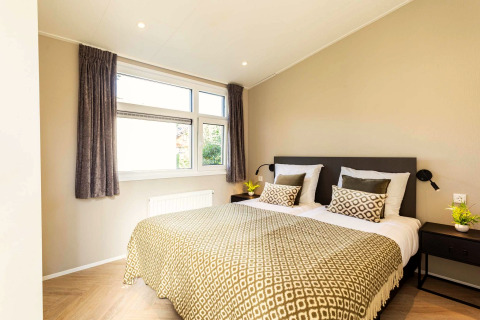 Moderne slaapkamer in Silva Wellness-lodge te Bospark Ede met tweepersoonsbed, kussens en daglicht.