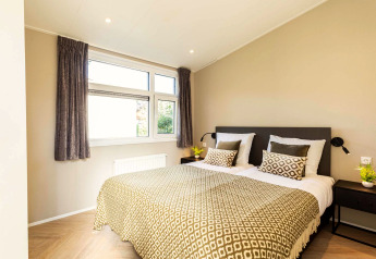 Dormitorio moderno en Silva Wellness lodge de Bospark Ede con cama doble, cojines y luz natural abundante.