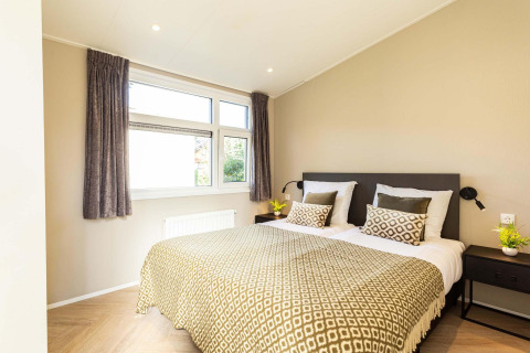 Moderne slaapkamer in Silva Wellness-lodge te Bospark Ede met tweepersoonsbed, kussens en daglicht.