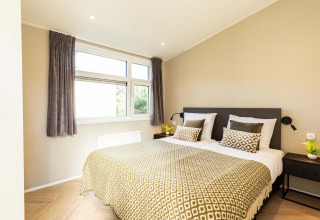 Moderne slaapkamer in Silva Wellness-lodge in Bospark Ede met dubbel bed, kussens en veel daglicht.