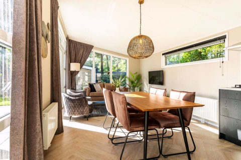 Licht woon- en eetgedeelte in de Silva Wellness lodge, modern ingericht met grote ramen in Bospark Ede.