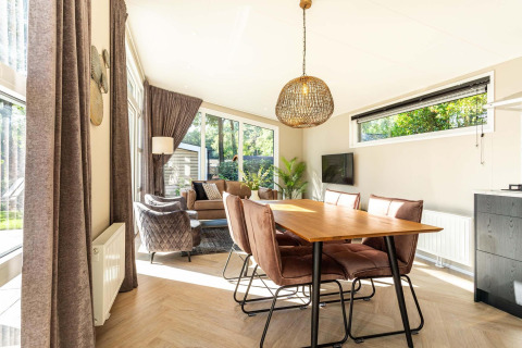 Luminoso salón-comedor en la cabaña Silva Wellness con decoración moderna y grandes ventanales en Bospark Ede.