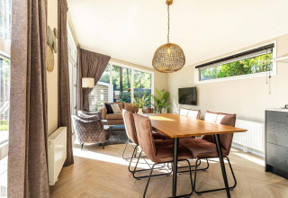 Luminoso salón-comedor en la cabaña Silva Wellness con decoración moderna y grandes ventanales en Bospark Ede.