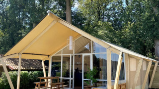 Tienda safari Luna Lodge en Camping the Noetselerberg, Países Bajos, con terraza y asientos de madera.