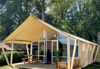 Tenda safari Luna Lodge al Camping the Noetselerberg nei Paesi Bassi con veranda in legno e area salotto.