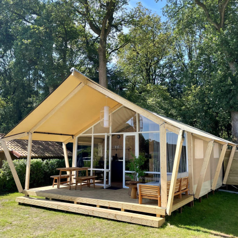 Safaritent Luna Lodge op Camping the Noetselerberg in Nederland met houten veranda en buitenzitje.