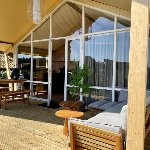 Safaritent Luna Lodge op Camping de Noetselerberg in Nederland, houten terras en moderne zitmeubels.