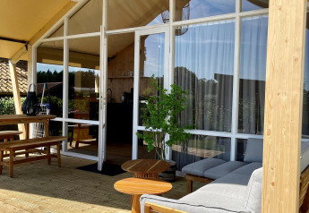 Safari-Zelt Luna Lodge auf Camping the Noetselerberg in den Niederlanden mit Terrasse und Holzmöbeln.