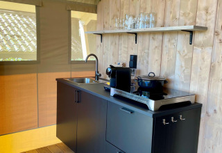Moderne tekøkken i safariteltet Luna Lodge på Camping de Noetselerberg, Nederlandene, med sorte skabe.