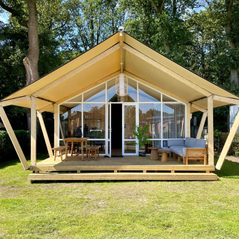 Tienda safari Luna Lodge en Camping the Noetselerberg, Países Bajos, con terraza de madera y muebles.