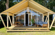 Tienda safari Luna Lodge en Camping the Noetselerberg, Países Bajos, con terraza de madera y muebles.