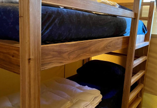 Literas con ropa de cama azul oscuro en la tienda safari Luna Lodge en Camping the Noetselerberg, Países Bajos.