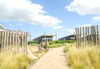 Pad richting Comfort Lodge op Kompas Camping Nieuwpoort in België, omringd door gras en blauwe lucht.