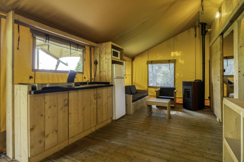 Interior de la tienda safari Stardust 40 Family Lodge en Arden Parks, Signy l'Abbaye, Francia, con muebles de madera.