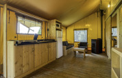 Interior de la tienda safari Stardust 40 Family Lodge en Arden Parks, Signy l'Abbaye, Francia, con muebles de madera.