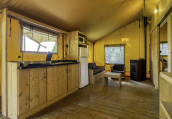 Interior view of Stardust 40 Family Lodge safari tent at Arden Parks, Signy l'Abbaye, France, with wooden furniture.