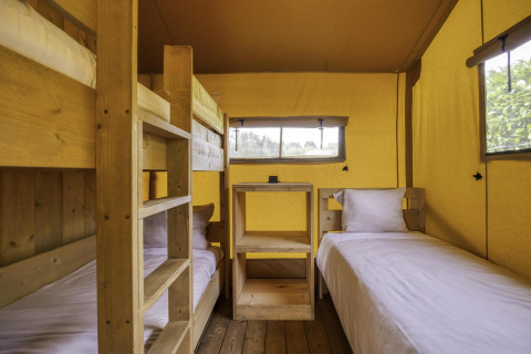 Interior of Stardust 40 Family Lodge safari tent with bunk bed and twin beds at Arden Parks, Signy l'Abbaye.