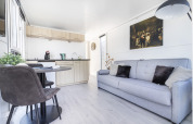 Lyst interiør af husbåd med moderne køkken, spisebord og sofa ved Harbour Lodge Amsterdam, Marina Parcs.
