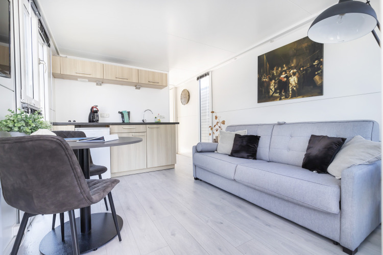 Intérieur lumineux de péniche avec cuisine moderne, table à manger et canapé au Harbour Lodge Amsterdam.