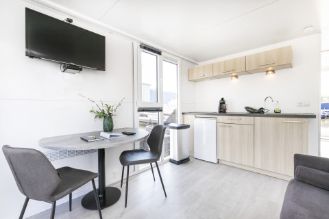 Espace salon moderne et kitchenette sur une péniche à Harbour Lodge Amsterdam, intérieur lumineux et confortable.