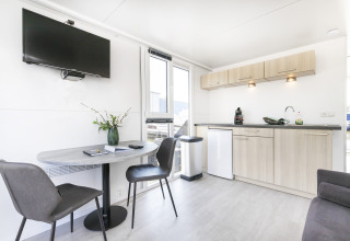 Sala de estar moderna y cocina en una casa flotante en Harbour Lodge Amsterdam, diseño luminoso y confortable.