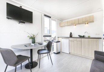 Moderne stue og tekøkken på en husbåd ved Harbour Lodge Amsterdam, lyst interiør og komfortabel stil.