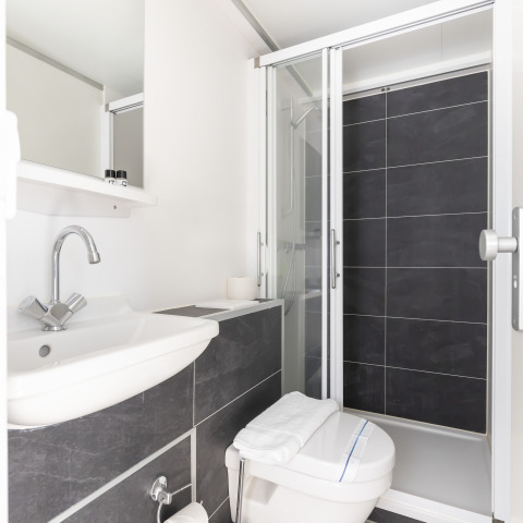 Salle de bain moderne sur la péniche Harbour Lodge Amsterdam avec douche, lavabo et toilettes.