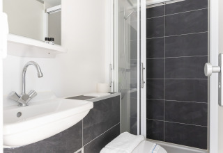 Salle de bain moderne sur la péniche Harbour Lodge Amsterdam avec douche, lavabo et toilettes.