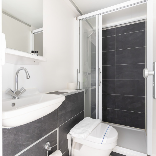 Modern bathroom on Harbour Lodge Amsterdam houseboat with shower, sink, and toilet at Marina Parcs.
