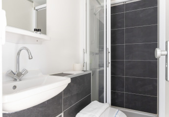 Baño moderno en la casa flotante Harbour Lodge Amsterdam con ducha, lavabo y WC en Marina Parcs.