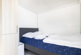 Dormitorio en la casa flotante Harbour Lodge Amsterdam en Marina Parcs, diseño moderno y sencillo.