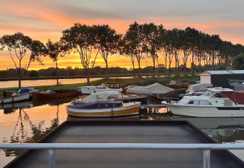 Husbåd i Marina Parcs Amsterdam med flere både i solnedgang, set fra Harbour Lodge Amsterdam, Holland.